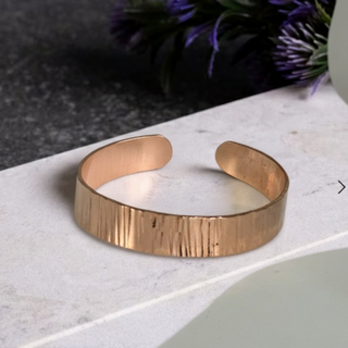 Rose gold bracelet on a white surface with a blurred background
