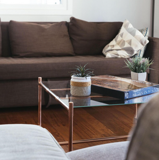 Industrial-style coffee table with copper piping details and a modern glass top, perfect for loft or contemporary spaces.