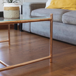 Side view of the copper and glass coffee table showcasing its handcrafted design and clean lines.