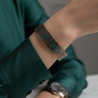 Close-up of a wrist wearing a decorative band with green accents, with a blurred background.
